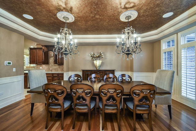 dining area featuring a wainscoted wall, a tray ceiling, a chandelier, and dark wood-style flooring