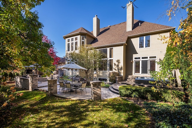 back of property featuring a patio area, a chimney, a lawn, and roof with shingles