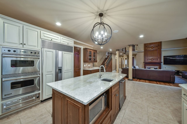 kitchen featuring light stone counters, a warming drawer, light tile patterned floors, a sink, and built in appliances