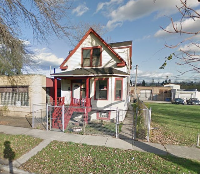 view of front of property with a porch, a fenced front yard, a front yard, and a gate