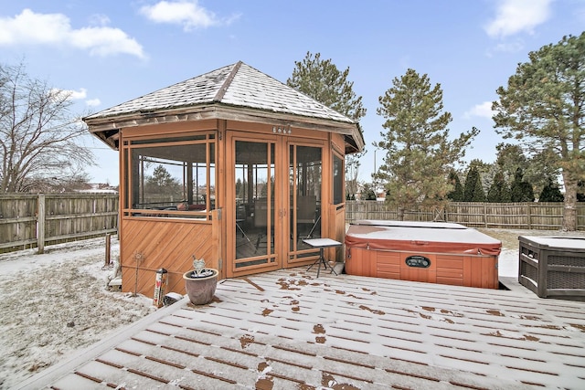 view of outbuilding with a fenced backyard, a hot tub, and a gazebo