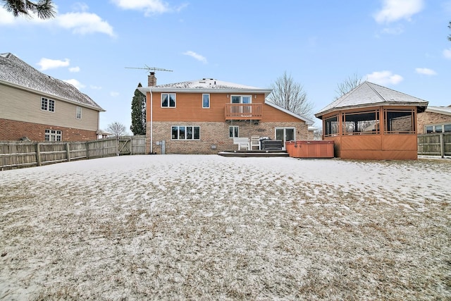 back of house featuring a hot tub, a fenced backyard, brick siding, and a chimney