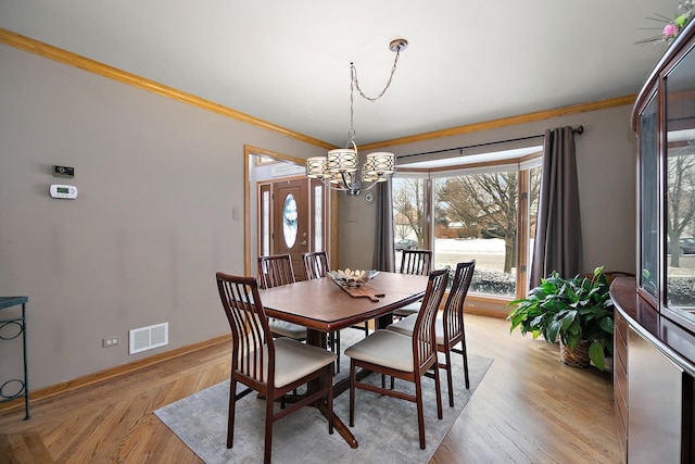 dining room featuring visible vents, an inviting chandelier, ornamental molding, light wood-type flooring, and baseboards