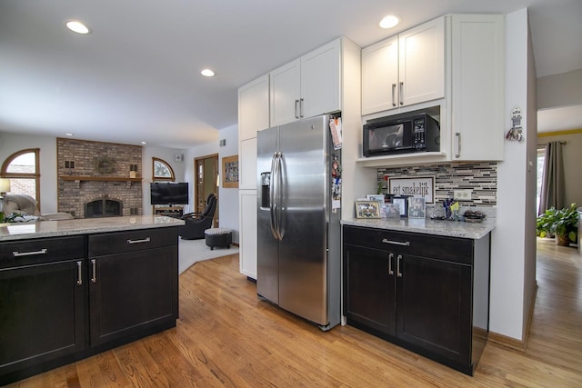 kitchen featuring black microwave, white cabinetry, backsplash, and stainless steel fridge with ice dispenser