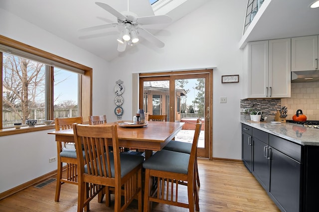 dining space featuring light wood-type flooring, visible vents, vaulted ceiling, and baseboards