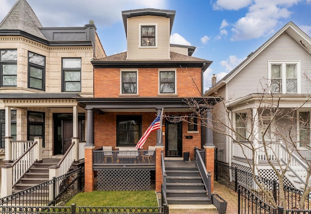 view of front of house featuring covered porch, brick siding, fence, and stairway