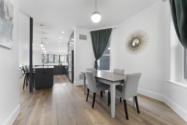 dining area featuring light wood-style floors, baseboards, and visible vents