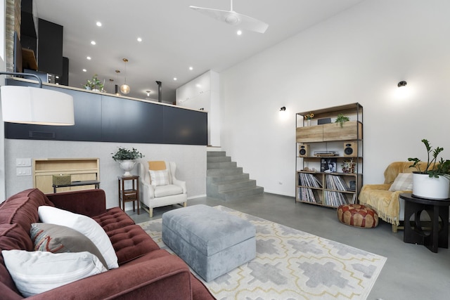 living room with visible vents, a towering ceiling, stairway, finished concrete floors, and recessed lighting