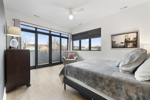 bedroom with multiple windows, wood finished floors, visible vents, and access to exterior