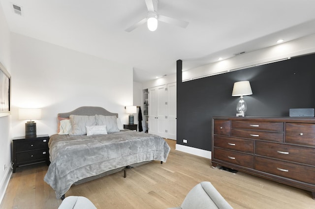 bedroom featuring light wood-type flooring, a barn door, visible vents, and baseboards