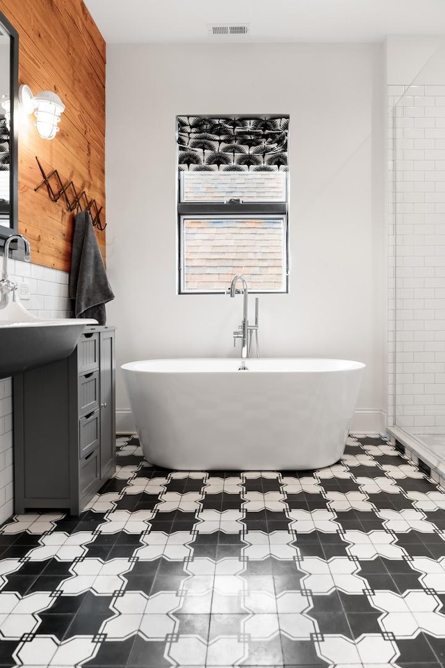 full bathroom featuring wood walls, visible vents, and a soaking tub