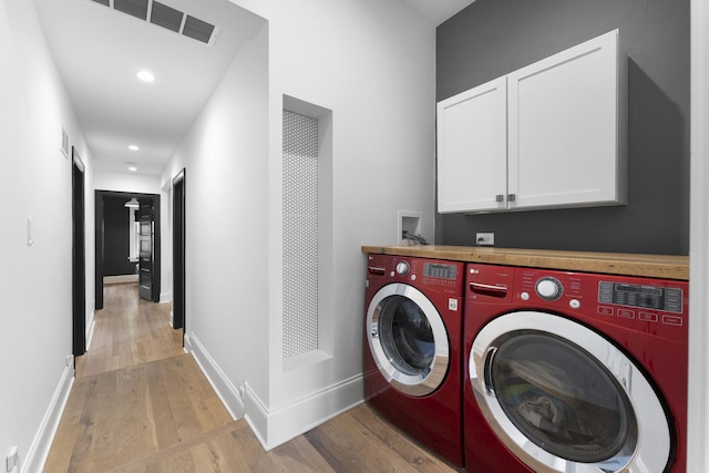 laundry area featuring light wood finished floors, washer and clothes dryer, and cabinet space