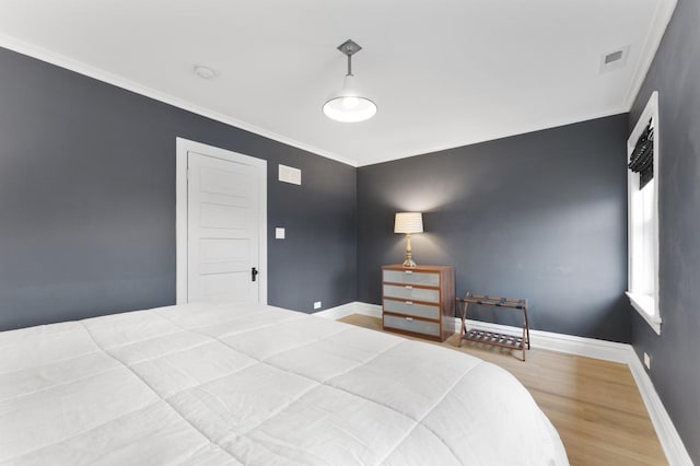 bedroom with crown molding, wood finished floors, visible vents, and baseboards