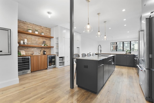 kitchen featuring light wood-type flooring, modern cabinets, wine cooler, and a sink