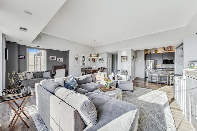 living area with light wood-style floors, visible vents, and baseboards