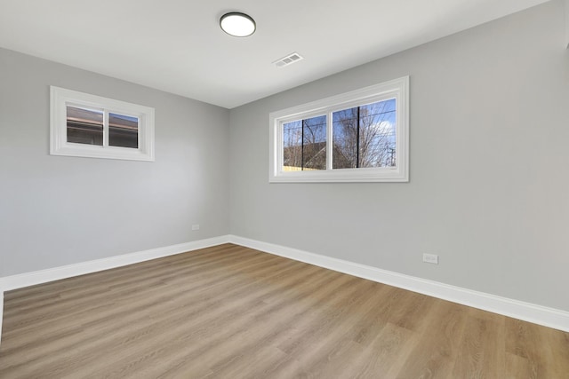 empty room with visible vents, baseboards, and wood finished floors