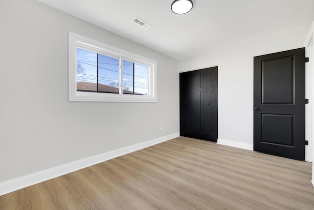 unfurnished bedroom featuring a closet, visible vents, light wood-style flooring, and baseboards