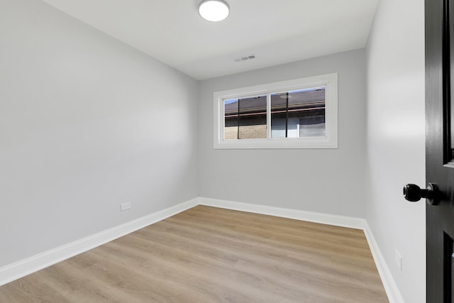 spare room featuring light wood finished floors, baseboards, and visible vents