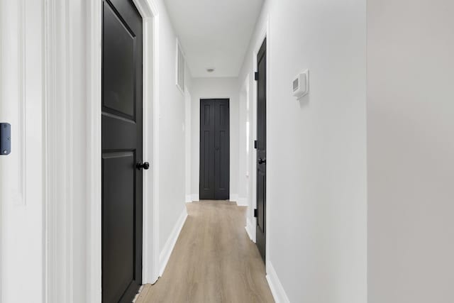 hallway with baseboards and light wood-style floors