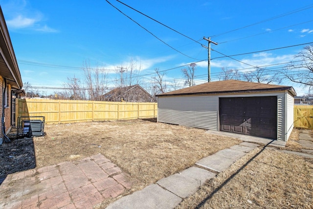 view of yard featuring an outbuilding, driveway, a detached garage, and fence