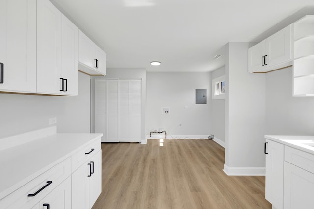 kitchen with light wood-style flooring, electric panel, white cabinetry, and light countertops