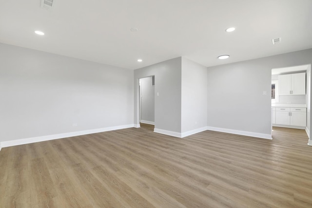 spare room with recessed lighting, visible vents, light wood-style flooring, and baseboards