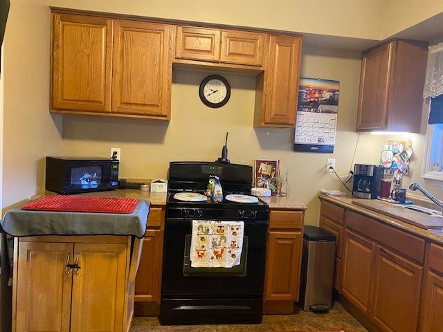 kitchen featuring black appliances, a sink, and brown cabinets