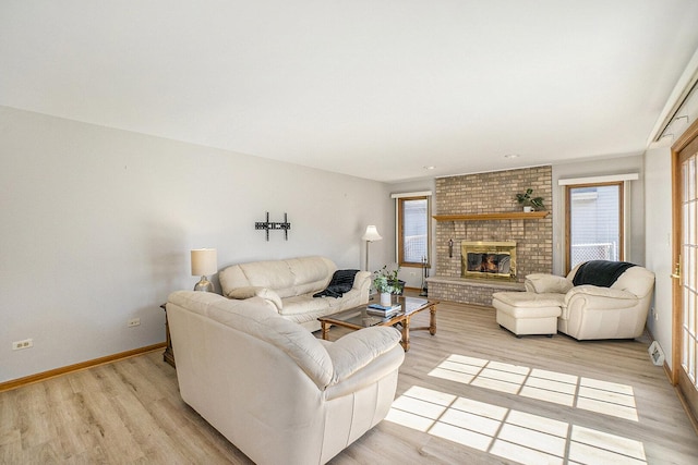 living area with light wood-type flooring, a fireplace, and baseboards