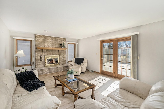 living area with light wood-style floors, a brick fireplace, visible vents, and baseboards