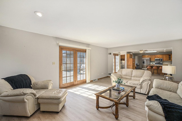 living room featuring light wood-style flooring, baseboards, and french doors