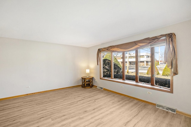 unfurnished room with light wood-type flooring, visible vents, and baseboards