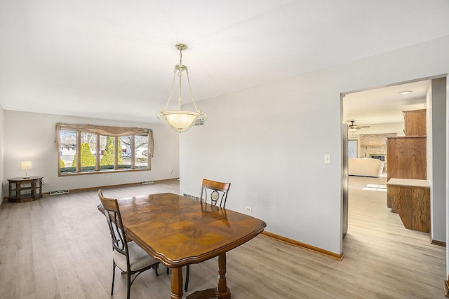 dining room with baseboards, visible vents, and light wood finished floors