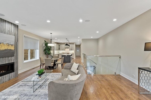 living room with recessed lighting, a fireplace, light wood-style flooring, and baseboards