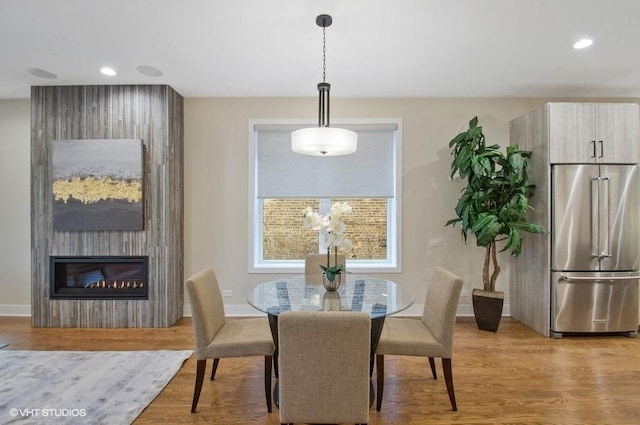 dining room featuring a fireplace, baseboards, wood finished floors, and recessed lighting