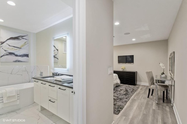 full bath featuring a washtub, recessed lighting, wood finished floors, vanity, and baseboards