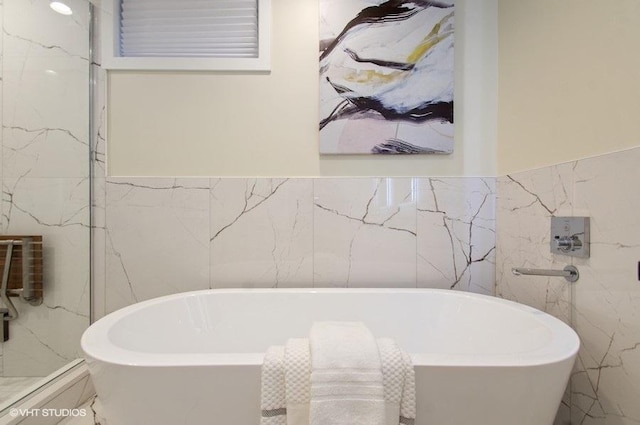 bathroom featuring a freestanding tub and tile walls