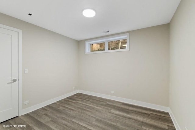 unfurnished room with wood finished floors, visible vents, and baseboards