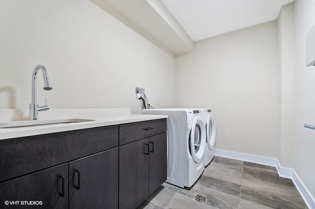 laundry room featuring cabinet space, baseboards, a sink, and independent washer and dryer