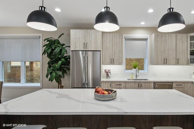 kitchen featuring a kitchen island, modern cabinets, high quality fridge, light stone counters, and a sink