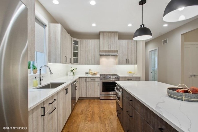 kitchen featuring light wood-style flooring, a sink, visible vents, appliances with stainless steel finishes, and light stone countertops