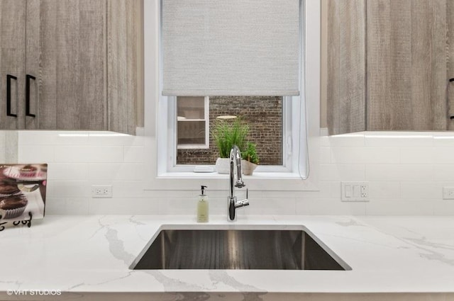 room details with light stone countertops, decorative backsplash, and a sink