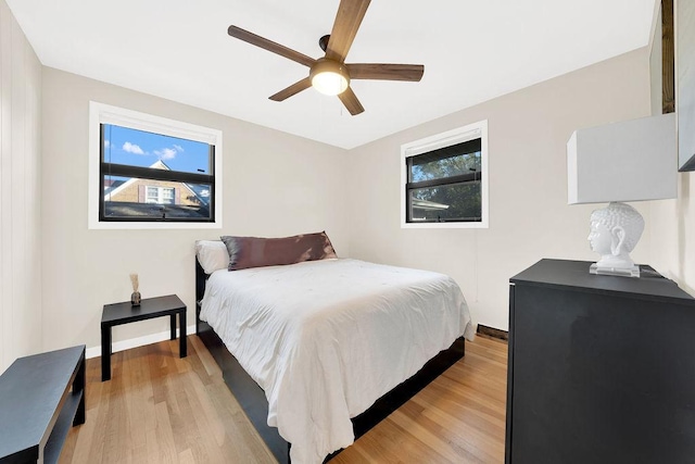 bedroom with ceiling fan, light wood-style flooring, and baseboards