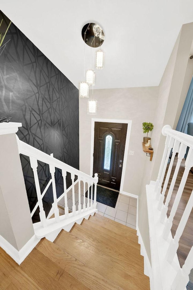 foyer entrance featuring stairs, an accent wall, baseboards, and wood finished floors