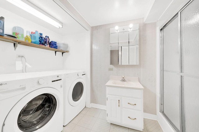 washroom featuring laundry area, separate washer and dryer, a sink, and tile walls