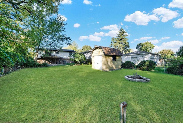 view of yard with a shed, fence, a fire pit, and an outdoor structure