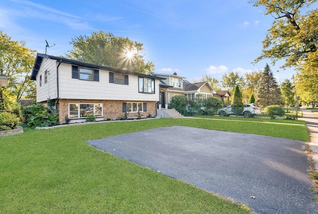 view of front of house featuring aphalt driveway, a front yard, and brick siding