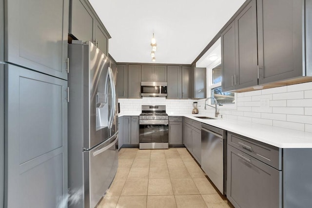 kitchen with light tile patterned floors, gray cabinets, backsplash, appliances with stainless steel finishes, and a sink