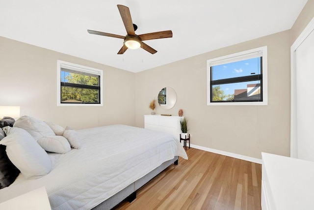 bedroom featuring ceiling fan, light wood-style flooring, and baseboards