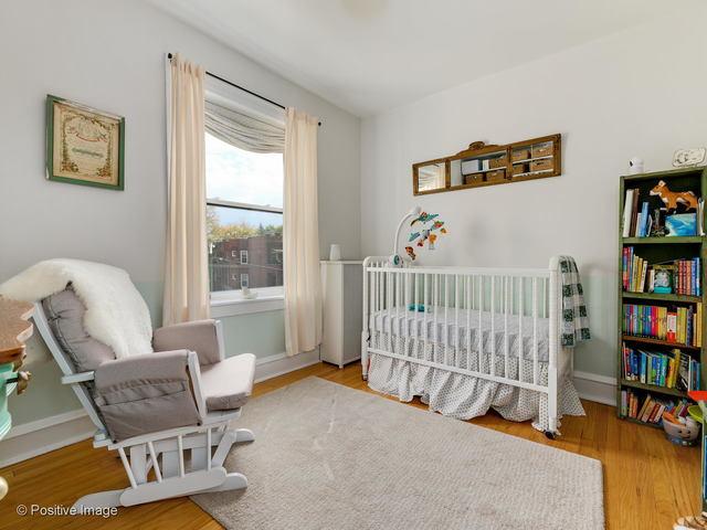 bedroom featuring a nursery area, wood finished floors, and baseboards