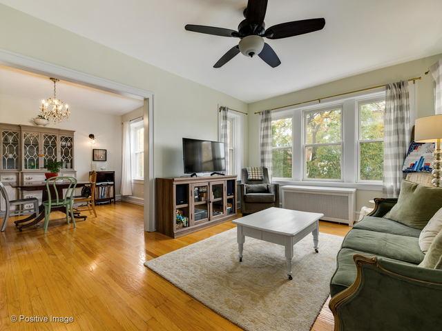 living area featuring ceiling fan with notable chandelier, wood finished floors, and radiator